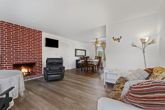 living room with ceiling fan, dark hardwood / wood-style flooring, and a brick fireplace