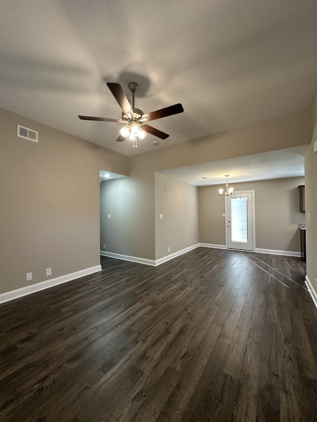 spare room with ceiling fan with notable chandelier and dark hardwood / wood-style flooring