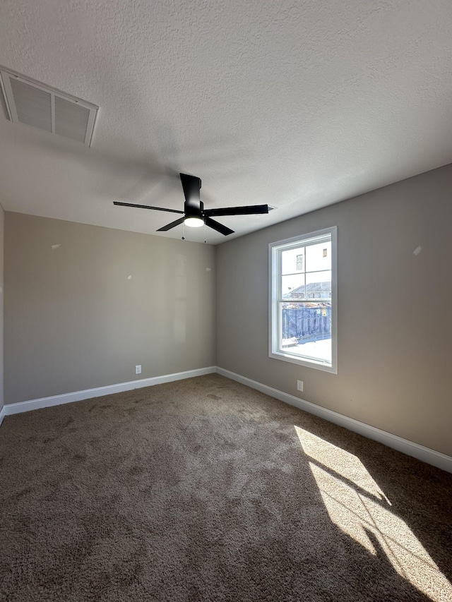 carpeted empty room with ceiling fan, a textured ceiling, visible vents, and baseboards