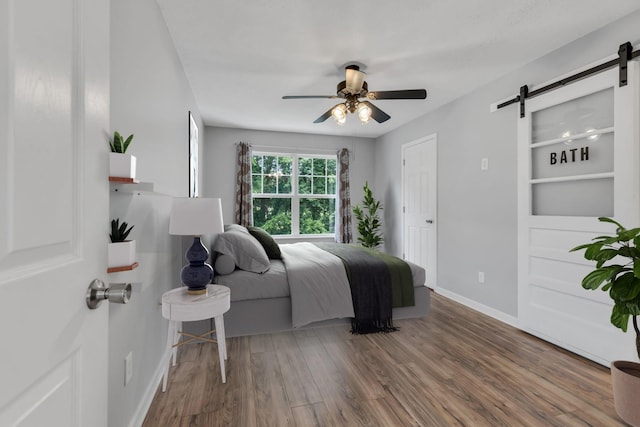 bedroom featuring a barn door, hardwood / wood-style flooring, and ceiling fan