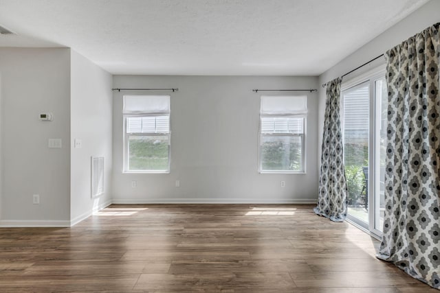 spare room with dark hardwood / wood-style flooring, plenty of natural light, and a textured ceiling