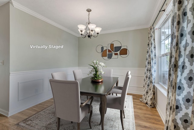 dining room with ornamental molding, light hardwood / wood-style flooring, and a notable chandelier