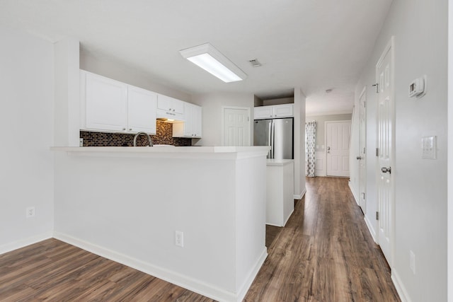 kitchen featuring kitchen peninsula, stainless steel fridge, and white cabinetry