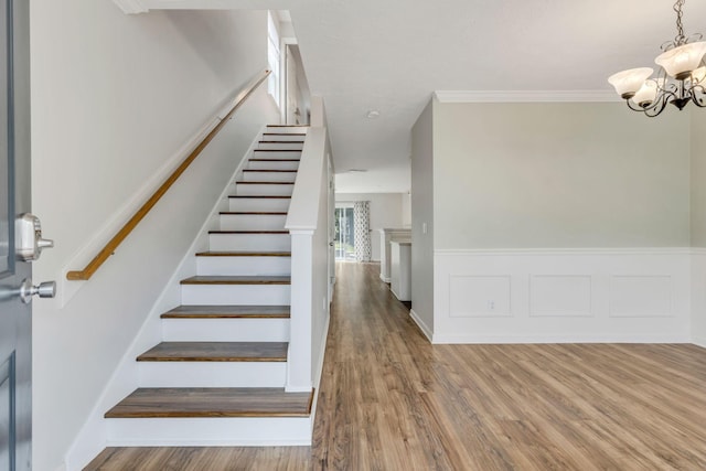 stairway with ornamental molding, a chandelier, and hardwood / wood-style flooring