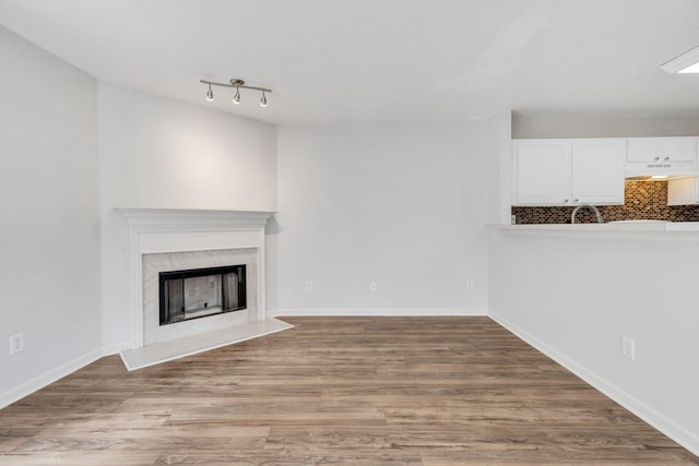 unfurnished living room featuring a fireplace, hardwood / wood-style floors, and track lighting