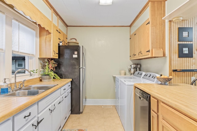 laundry area featuring washer and dryer, light tile patterned flooring, crown molding, and sink