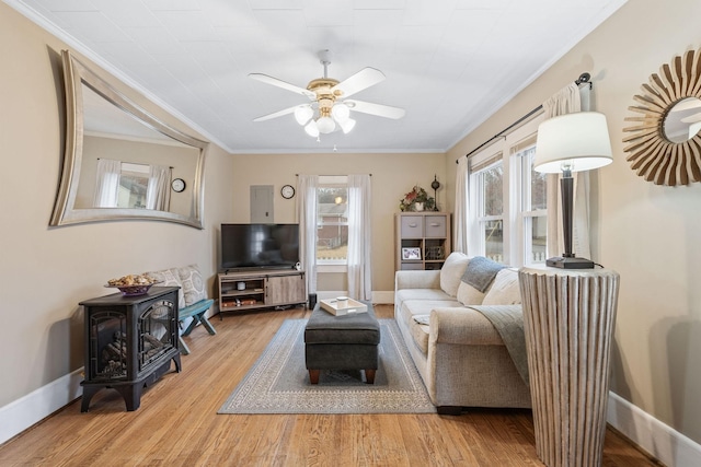 living room with a wealth of natural light, crown molding, ceiling fan, and light wood-type flooring