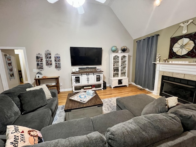 living room with hardwood / wood-style flooring, ceiling fan, a fireplace, and high vaulted ceiling