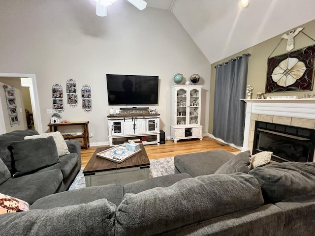 living room with a tile fireplace, ceiling fan, hardwood / wood-style floors, and high vaulted ceiling