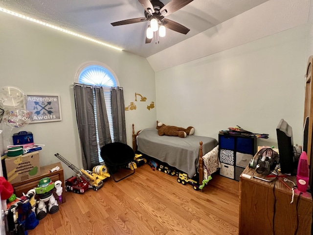 bedroom with ceiling fan, vaulted ceiling, and light hardwood / wood-style flooring