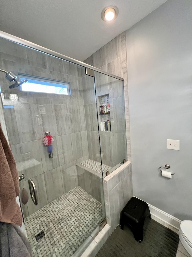 bathroom with tile patterned flooring, a shower with shower door, and toilet