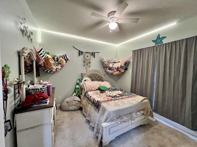 carpeted bedroom featuring ceiling fan and a textured ceiling