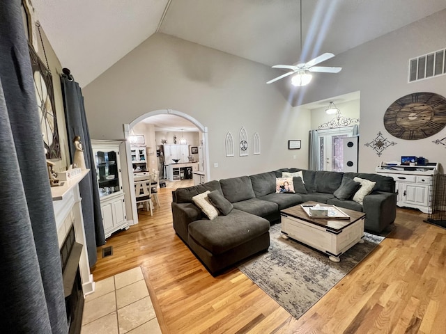 living room featuring ceiling fan, high vaulted ceiling, and light wood-type flooring