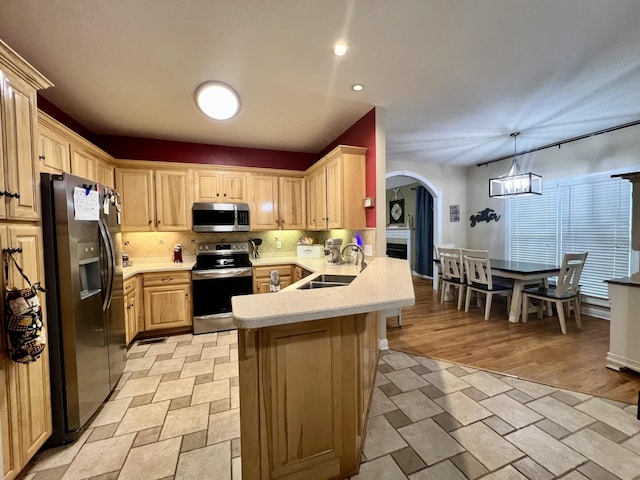 kitchen featuring light brown cabinets, sink, light hardwood / wood-style floors, kitchen peninsula, and stainless steel appliances