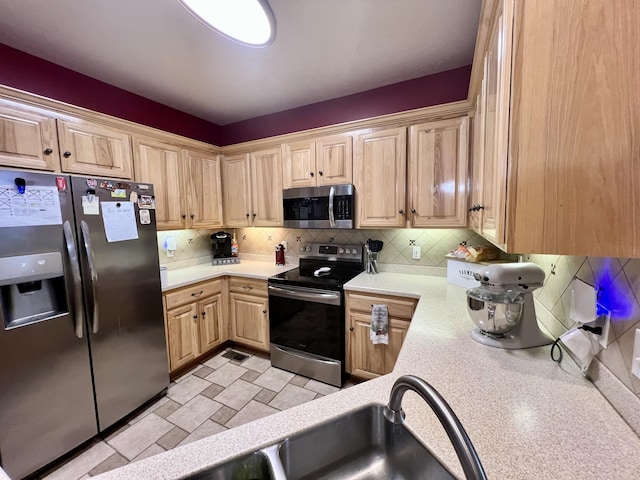 kitchen with light brown cabinets, sink, stainless steel appliances, and tasteful backsplash