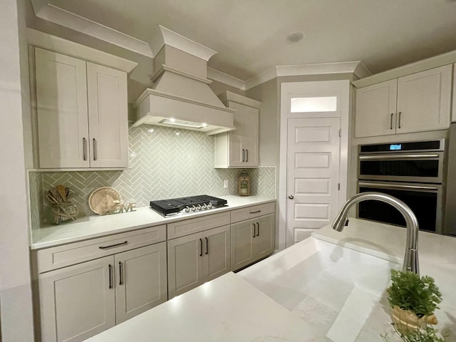 kitchen with decorative backsplash, appliances with stainless steel finishes, custom exhaust hood, sink, and white cabinets