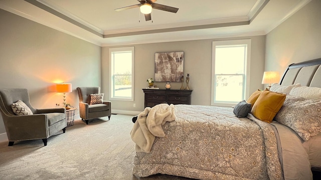 carpeted bedroom featuring ceiling fan, ornamental molding, a tray ceiling, and multiple windows