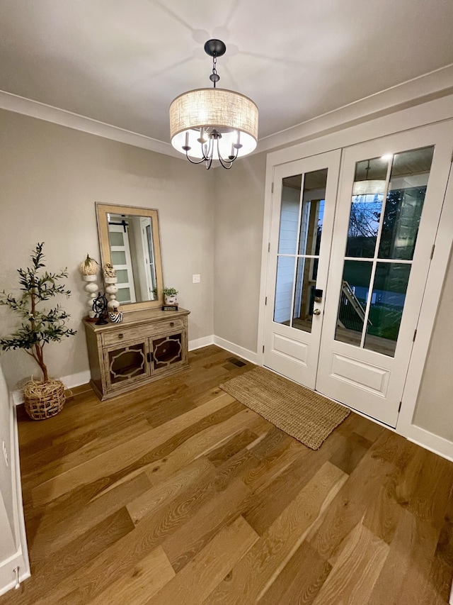 doorway to outside with crown molding, hardwood / wood-style floors, french doors, and an inviting chandelier