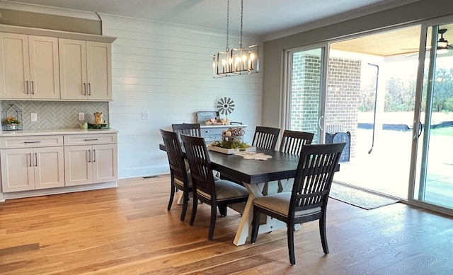 dining space with light hardwood / wood-style floors and wooden walls