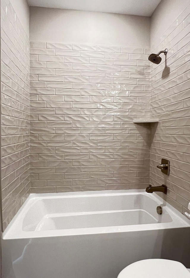 bathroom with tiled shower / bath combo and toilet