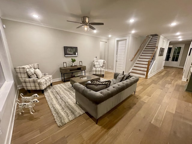 living room featuring ceiling fan, ornamental molding, and light wood-type flooring