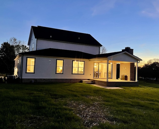 back house at dusk featuring a yard and a patio