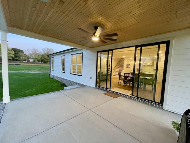 patio terrace at dusk with ceiling fan and a lawn