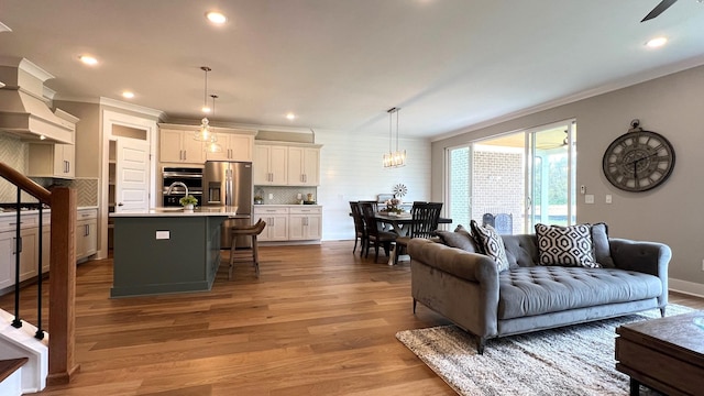 living room with light hardwood / wood-style flooring, ceiling fan, and crown molding