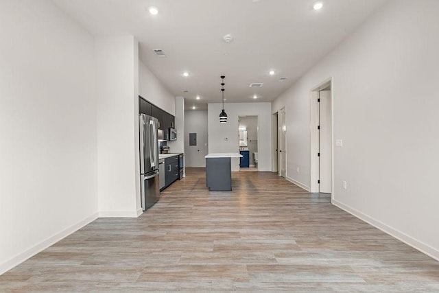 kitchen with stainless steel appliances, a kitchen island, pendant lighting, and light hardwood / wood-style floors