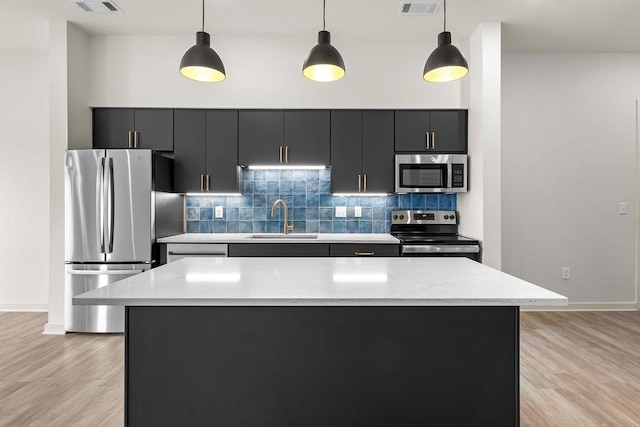 kitchen with decorative light fixtures, light hardwood / wood-style floors, sink, and stainless steel appliances