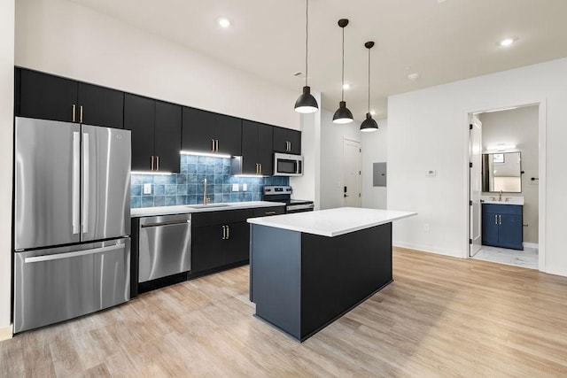 kitchen with stainless steel appliances, sink, decorative light fixtures, light hardwood / wood-style flooring, and a kitchen island