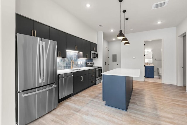 kitchen with sink, hanging light fixtures, light wood-type flooring, appliances with stainless steel finishes, and a kitchen island