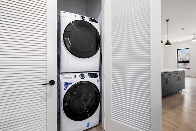 washroom featuring ceiling fan, stacked washer / drying machine, and light wood-type flooring