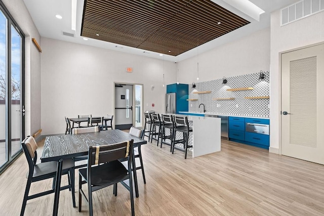 dining room with light hardwood / wood-style flooring, a high ceiling, and sink