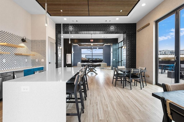 interior space featuring dishwasher, a center island, decorative light fixtures, a breakfast bar, and light wood-type flooring