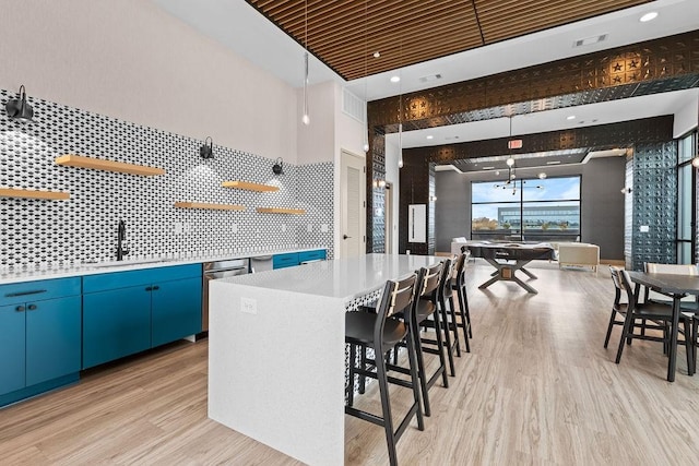 kitchen featuring light wood-type flooring, blue cabinets, sink, billiards, and a kitchen island