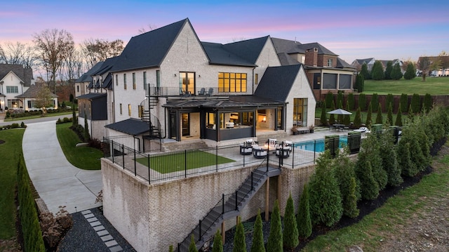 back house at dusk with an outdoor living space, a fenced in pool, and a patio