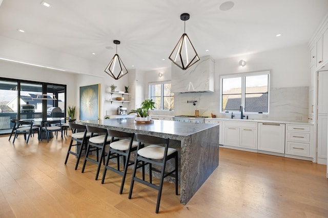 kitchen featuring a center island, decorative light fixtures, white cabinetry, and plenty of natural light