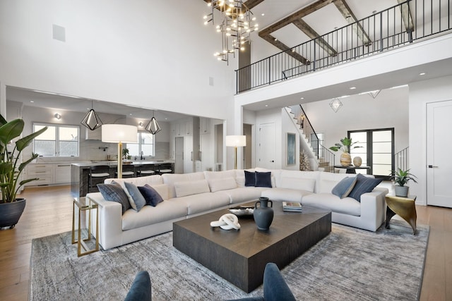 living room featuring light wood-type flooring, a towering ceiling, and a chandelier