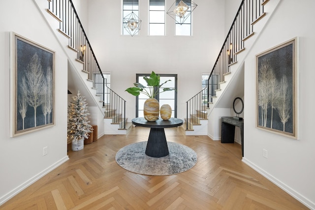 foyer featuring a chandelier, a high ceiling, light parquet flooring, and a wealth of natural light