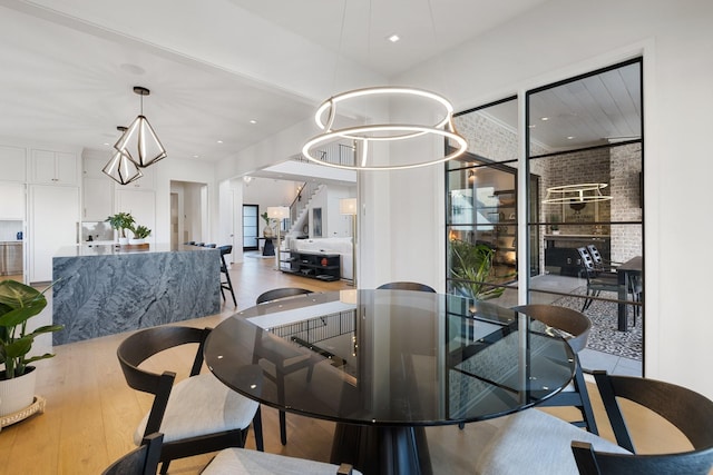 dining area featuring wood-type flooring, brick wall, and a chandelier