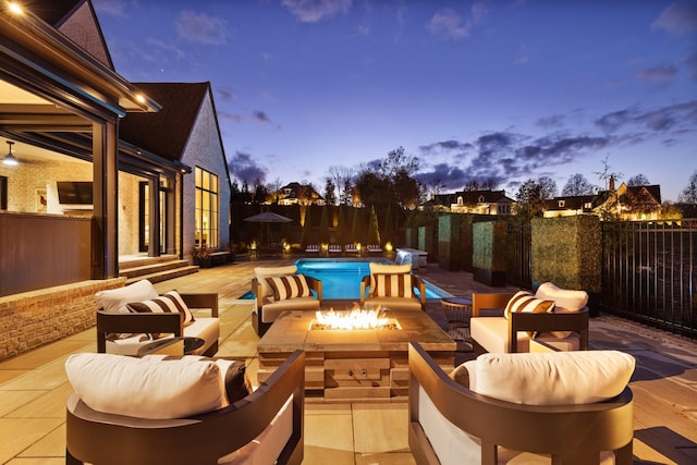 pool at dusk with a patio area and an outdoor living space with a fire pit