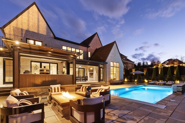 pool at dusk featuring an outdoor living space with a fire pit, pool water feature, and a patio