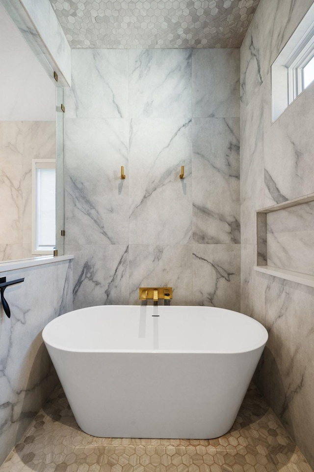 bathroom featuring a bathing tub, a healthy amount of sunlight, and tile walls