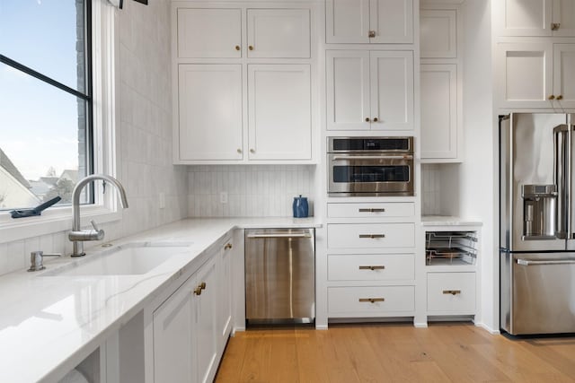 kitchen with white cabinets, light hardwood / wood-style floors, sink, and appliances with stainless steel finishes