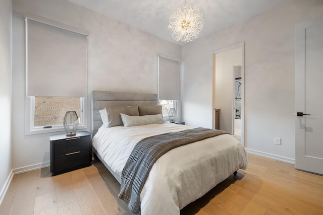 bedroom featuring an inviting chandelier, ensuite bathroom, and light hardwood / wood-style flooring