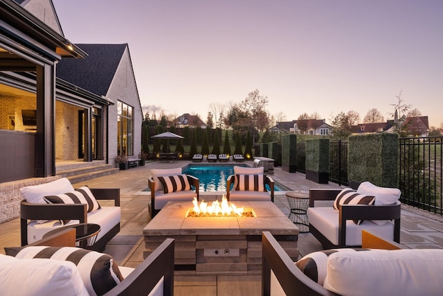 patio terrace at dusk with a fenced in pool and an outdoor living space with a fire pit