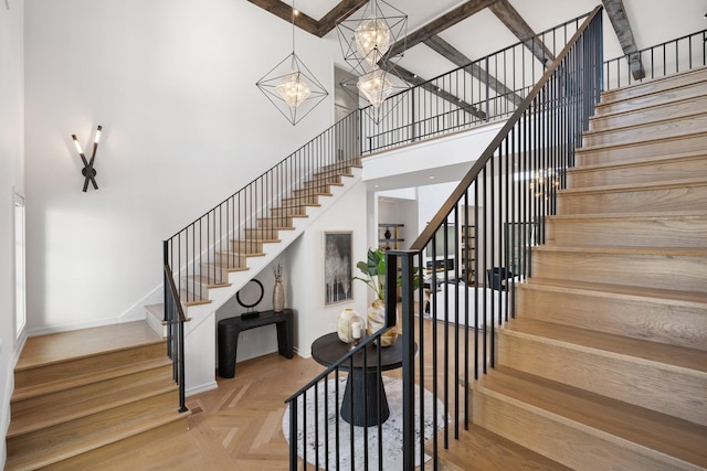 stairs with parquet flooring, a high ceiling, and a notable chandelier