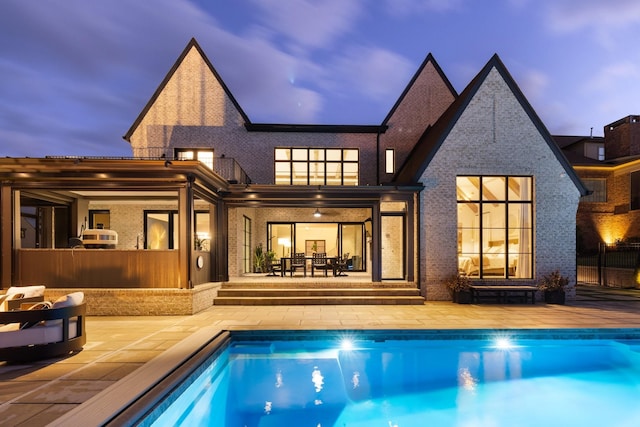 back house at dusk featuring a patio and a fenced in pool