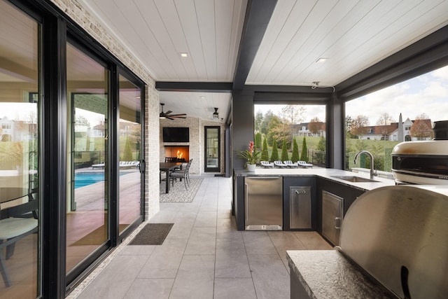 interior space featuring an outdoor stone fireplace, sink, area for grilling, and exterior kitchen